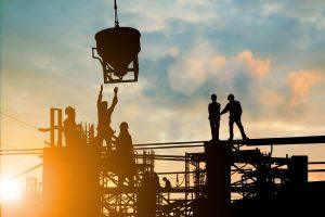 Silhouette of engineer and construction team working at site over blurred background sunset 